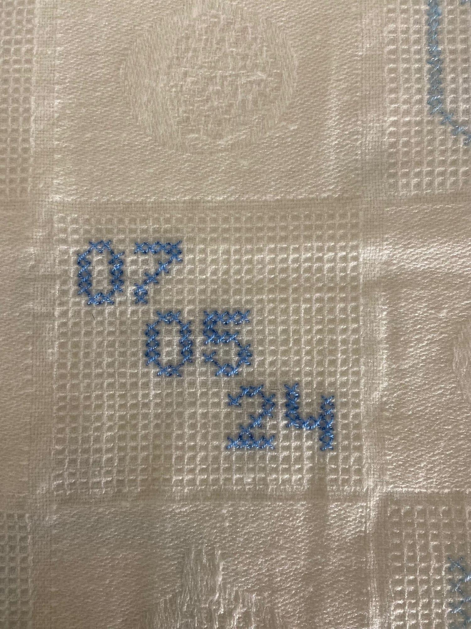 Close-up of 07/05/24 birth date cross-stitched on blanket