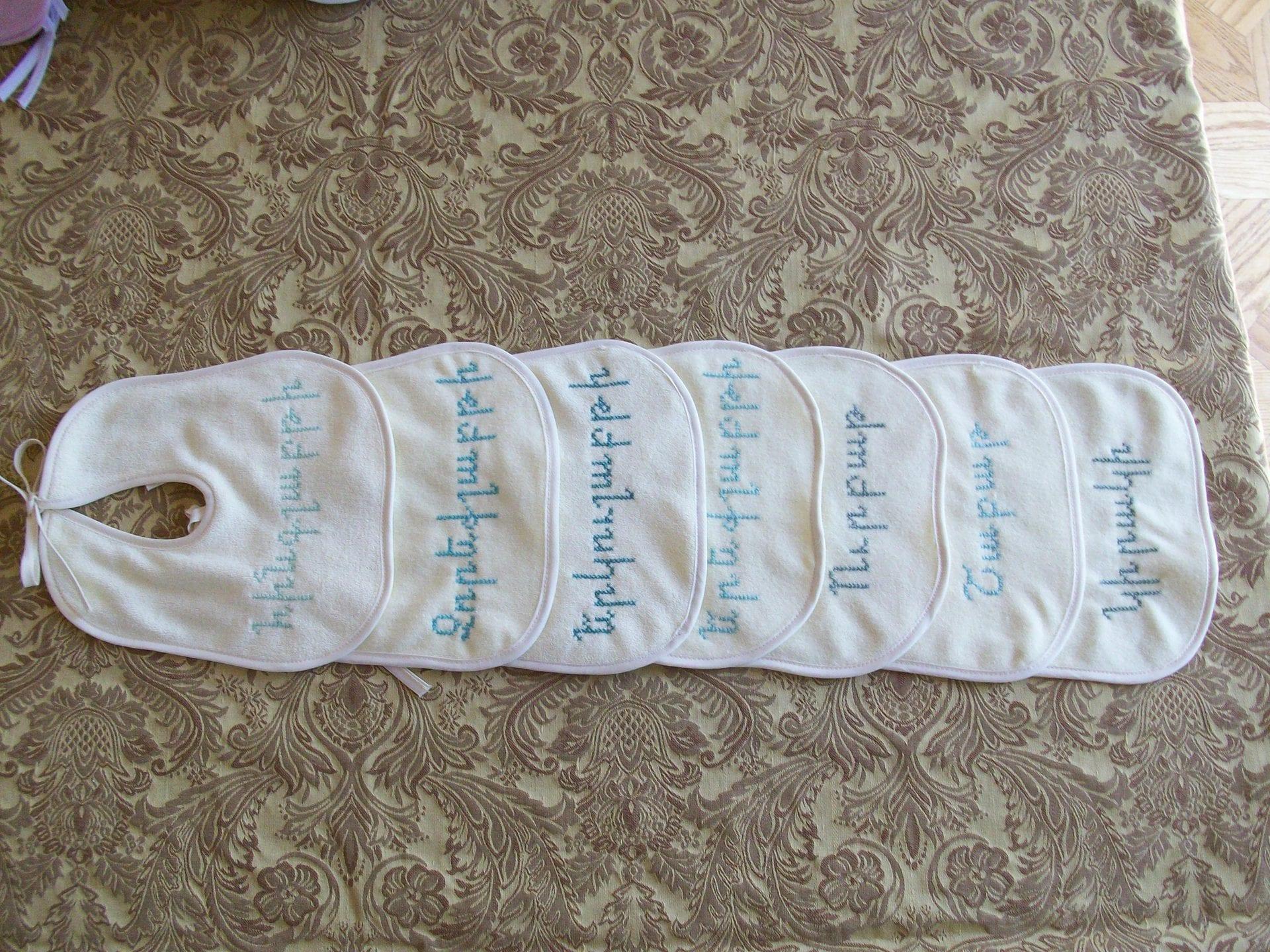 Set of cross-stitched baby bibs arranged in a fan